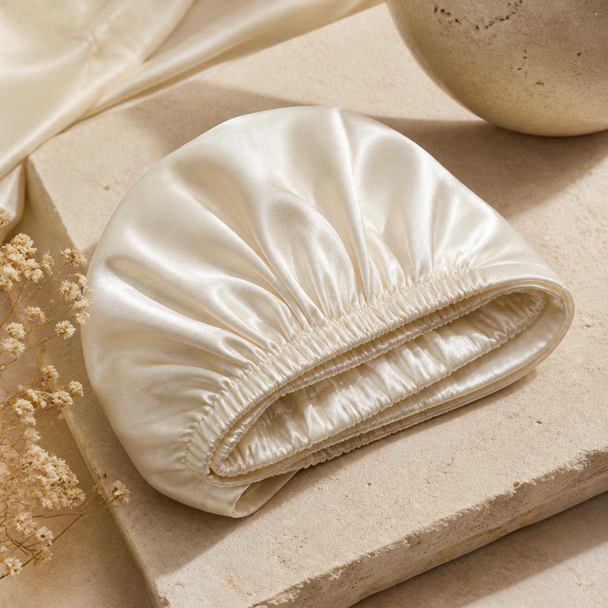 Ivory silk sleep bonnet folded on pale stone